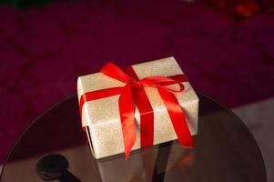 The golden gift box is tied with a red ribbon with a bow photo
