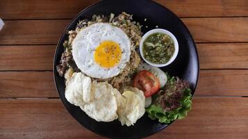 pueblo frito arroz o nasi goreng Kampung hecho con un montón de coberturas, tomate, frito huevo, crujiente, y especial aceitado mezcla chile algunos Fresco vegetal. foto