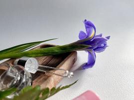 spa still life. dropper with anti-aging liquid. Skincare. Dropper on the background of tropical leaves and irises. photo
