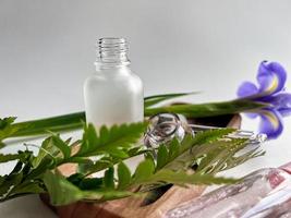 spa still life. dropper with anti-aging liquid. Skincare. Dropper on the background of tropical leaves and irises. photo