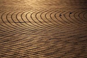 The texture of the sidewalk street in the sunlight. Brown rectangular tiles in perspective. Background. Horizontal. photo