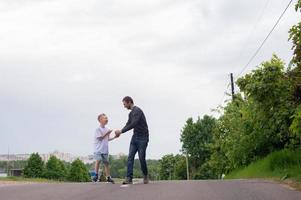 A father walks with his son on the road. The child is indulging photo