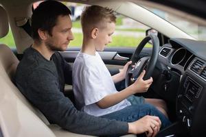 Dad shows his little son how to drive a car photo