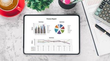 tableta con gráficos e informes en el lugar de trabajo de escritorio de oficina. vista superior plana foto