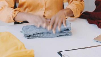 Moda diseñador l joven asiático mujer trabajando utilizando computadora portátil, tableta y sonriente mientras en pie en taller respondiendo en negocio video