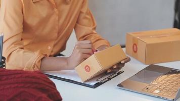 porträtt ung attraktiv hipster asiatisk kvinna ägare börja ring upp telefon med låda på Hem förbereda paket leverans i sme tillförsel kedja, anskaffning, asiatisk Omni-kanal sme e handel uppkopplad begrepp. video