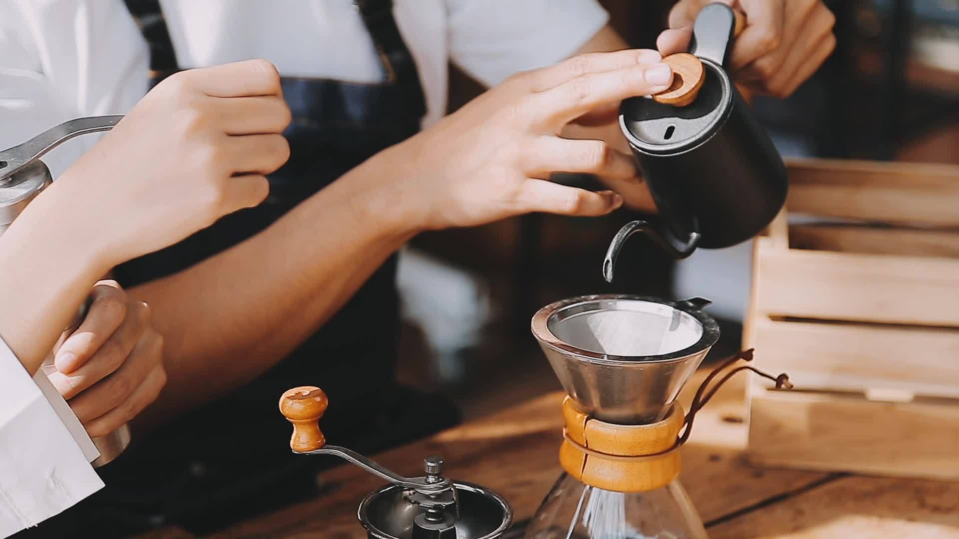 Hands of a barista making a pattern into a coffee drink using milk Hands of a barista making a pattern into a coffee drink using milk