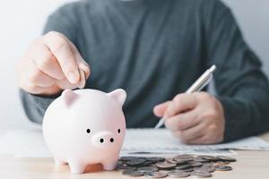 empresario poniendo moneda en el hucha en mesa, familia Finanzas plan concepto, recaudación de fondos, jubilación, donación, ahorro, caridad, inversión, financiero crisis concepto. foto