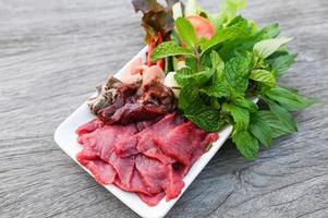 raw beef meat cuts slices on white plate and fresh vegetables fresh meat top view - beef  sashimi , beef liver asian thai food photo