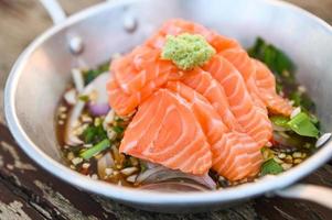 salmon fillet with wasabi on spicy sauce , fresh raw salmon salad on wooden table - Thai food photo