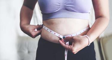 mujer gorda midiendo, mujer gorda gorda barriga gordita deporte recreación cuidado de la salud perder el concepto de grasa abdominal, mujer sosteniendo barriga excesiva con cinta métrica foto