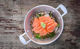 salmon fillet with wasabi on spicy sauce , fresh raw salmon salad on wooden table - Thai food photo