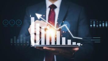 Businessman holding tablet bar graph of analytics and financial, Changes in new planning, Business growth, ideas and perspectives, Stock investment, and dividends yield from business in the new year photo