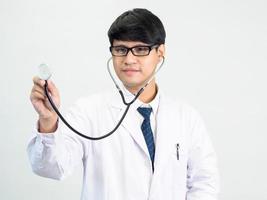 asiático hombre estudiante científico o médico uno persona, vistiendo un blanco vestido, de pie, mirando y sonriente, blanco antecedentes con un estetoscopio auscultando el corazón alrededor su cuello. foto