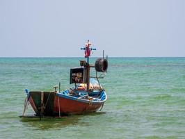 paisaje mirada vista pequeño barco de pesca de madera antiguo estacionado costa el mar. después de la pesca de los pescadores en el pequeño pueblo es pequeña pesca local. cielo azul, nubes blancas, clima despejado, playa phala, rayong foto