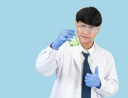 Asian man student scientist in reagent mixing laboratory In a science research laboratory with test tubes of various sizes. on the floor in  laboratory chemistry lab blue background. photo