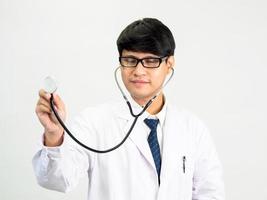 Asian man student scientist or doctor one person, wearing a white gown, standing, looking and smiling, white background with a stethoscope auscultating the heart around his neck. photo