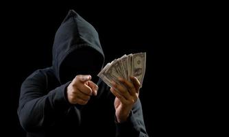 hacker espía hombre manos vistiendo un negro camisa, sentado en un silla y un mesa, es un ladrón, participación dinero, contando el cantidad adquirido desde secuestro o robando, en un negro azabache habitación. foto