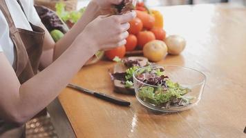 jong en gelukkig vrouw aan het eten gezond salade zittend Aan de tafel met groen vers ingrediënten binnenshuis video