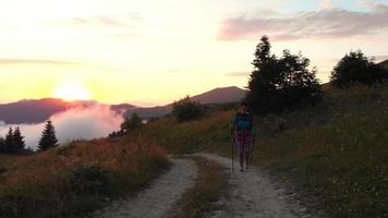 de face vue solo femelle caucasien promeneur randonneur sur forêt Piste sourire prendre plaisir spectaculaire le coucher du soleil plus de des nuages dans éloigné Caucase Montagne dans Géorgie chaud été soir