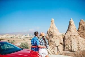 Young couple travelling with a red car on the desert photo