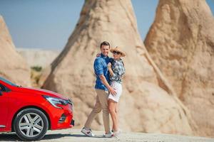 Young couple travelling with a red car on the desert photo