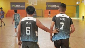 two basketball player touch his friend on basket ball competition photo