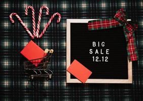 The text of the sale 12.12 on a message board with a gift box, credit card, mini grocery cart. Design to promote the winter sale at the end of the year. Top view. photo