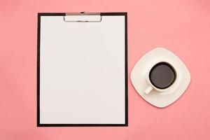 A tablet with space for your text on a pink background, next to a cup of coffee photo