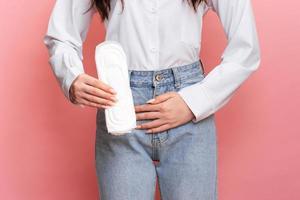 Studio shot of a young girl experiencing pain from menstruation with menstrual padding in her hands. Space for text. The concept of feminine hygiene. photo