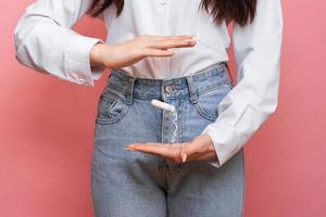 A studio shot of a girl holding a tampon in her hand in a menstrual applicator. The concept of feminine hygiene. photo