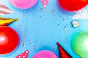 Colorful balloons and confetti on blue table top view. Festive or party background. photo