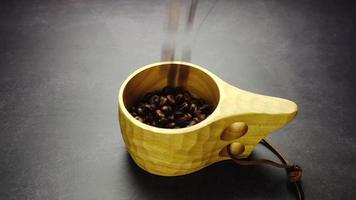Häll i de rostad kaffe bönor in i en trä- mugg. video