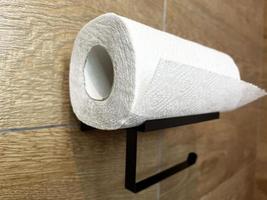 Roll of paper towel on the toilet shelf. Napkins on the background of a wooden wall. photo