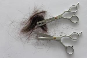 Hair and scissors for haircuts on white paper background. photo