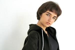 Young woman with black short hair posing in studio. Dressed in a black photo