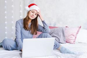 Caucasian young woman while working on laptop at home for Christmas in cozy photo