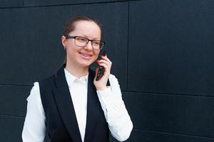 Successful businesswoman talking on mobile phone while walking outdoors near photo