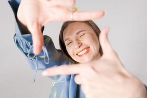 Close up portrait happy smiling woman with beaming smile framing with thumbs up photo