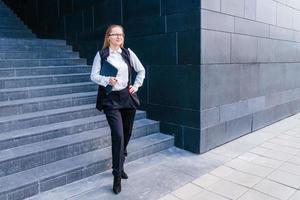 Business caucasian woman holding a laptop and outdoors surrounded by buildings. photo