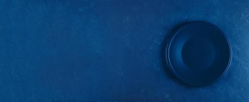 Empty plate on blue concrete background. Classic blue. Trend color of 2020 year. Banner for website photo