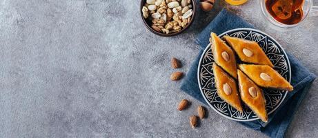 Baklava. Ramadan Dessert. Traditional Arabic dessert with nuts and honey, cup of tea on a concrete table photo