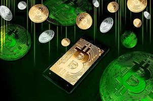 Smartphone with Bitcoin symbol on-screen among piles of golden and silver Bitcoins on green background photo