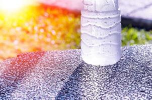 Plastic water bottle wet cold and clean with water droplets on a green background photo