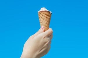 Woman hand holding  icecream on blue sky photo