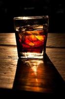 Cola with whiskey and ice on a wooden table background photo