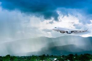 Airplane in the sky with rain over mountain, The plane flies in terrible thunderstorm,Concept of climate weather photo