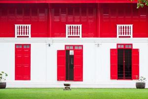 Vibrant red wooden windows with green grass,traditional red door wooden of an old on white wall,in Thailand photo