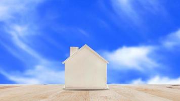 Small home model on wooden table with blue sky background.Family life and Business real estate concept. photo