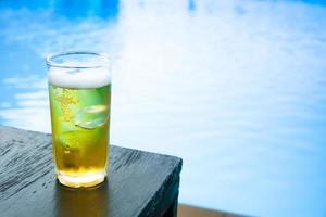 vaso de cerveza ligera en la mesa de madera en la piscina foto